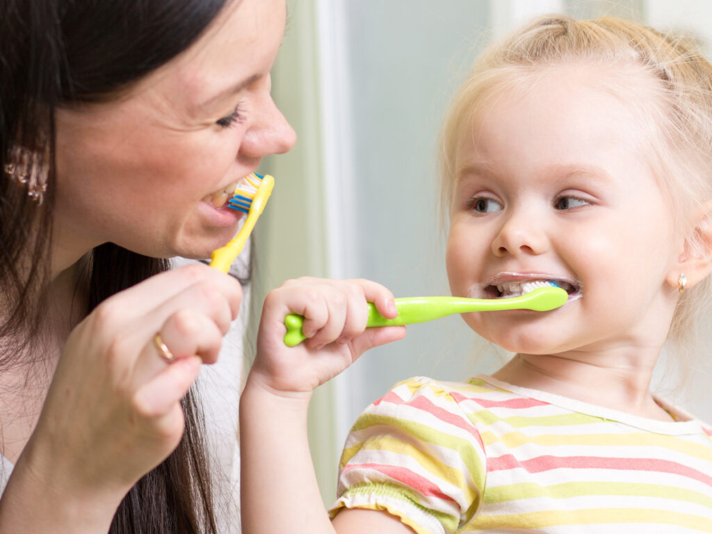 a mother brushing her teeth with her child