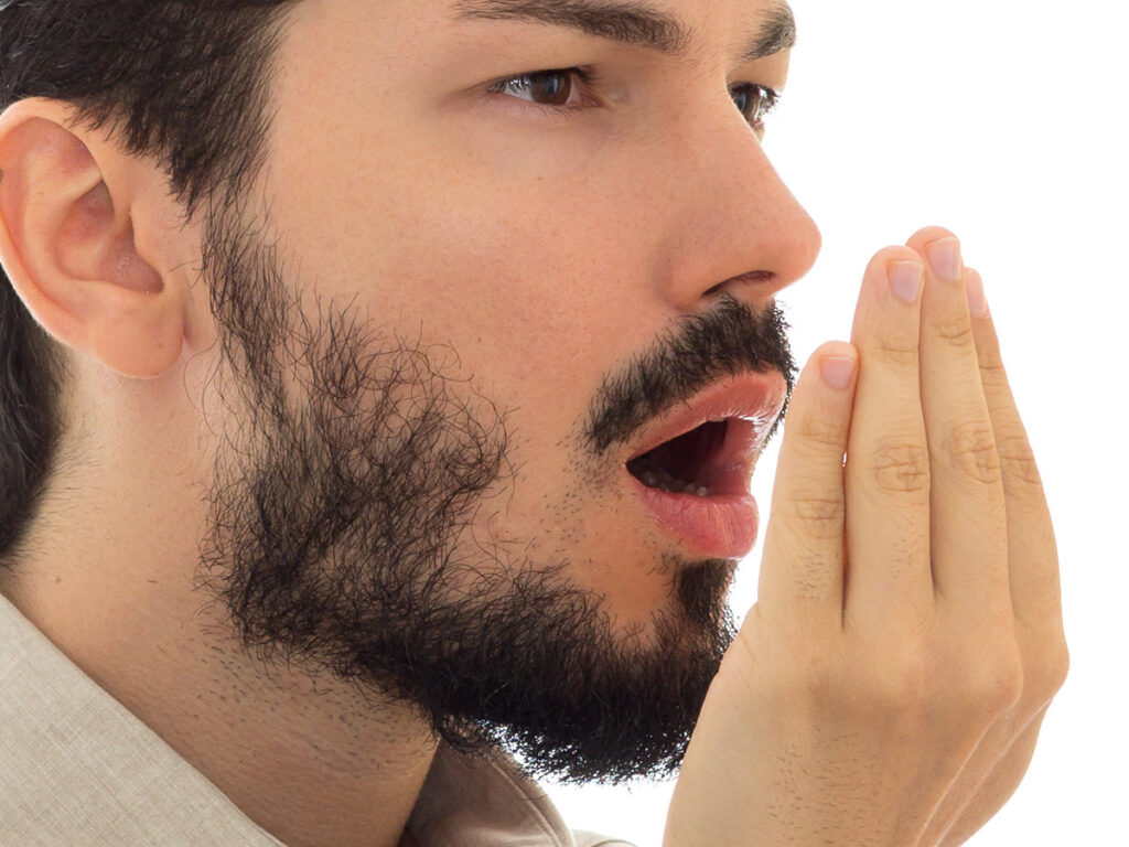 a man checking his breath with his hand