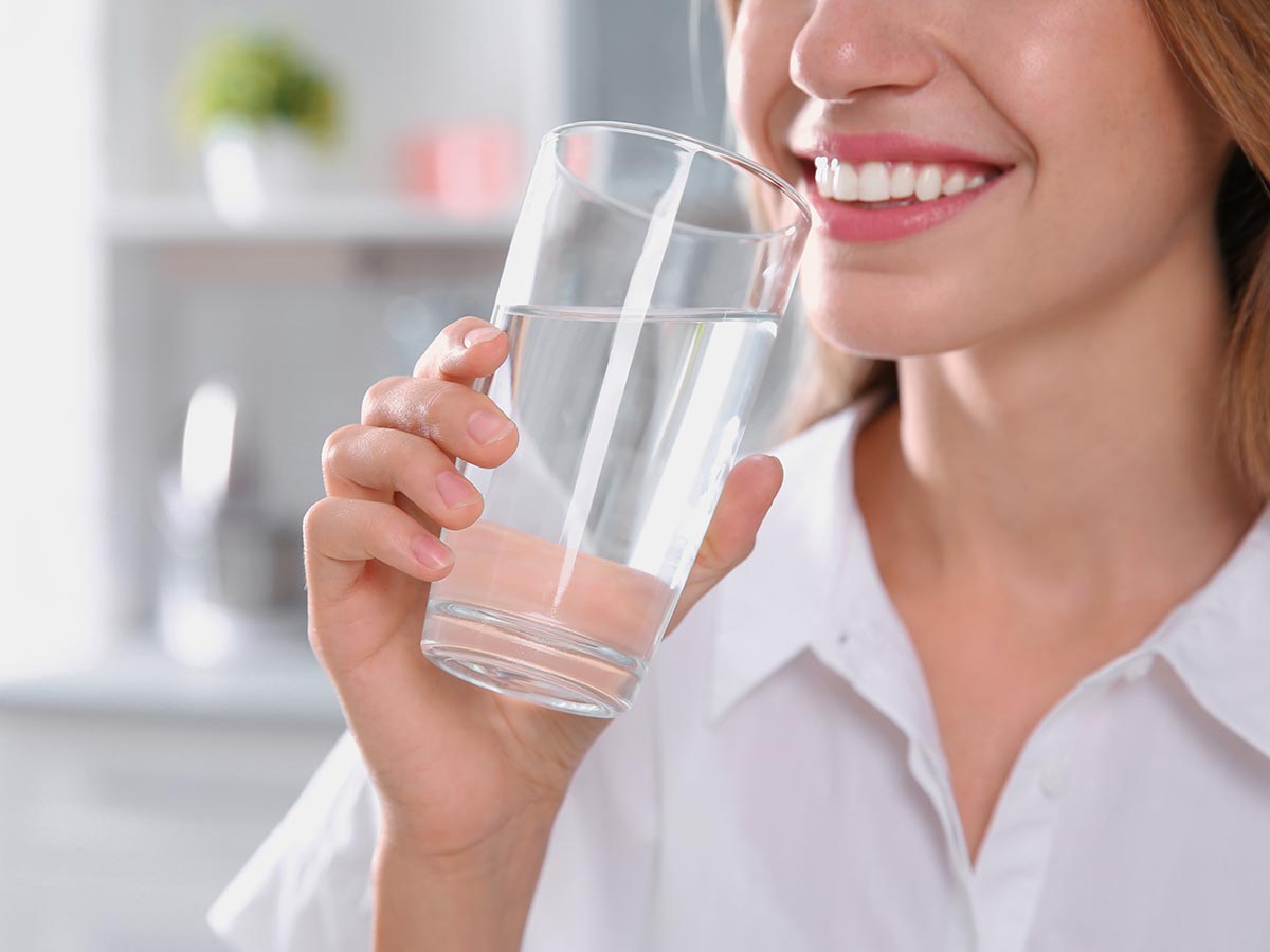 Smiling woman drinking a glass of water
