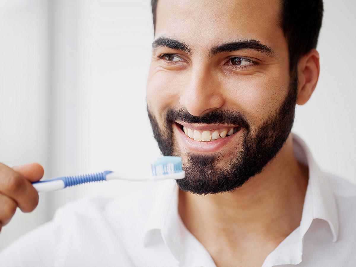 Smiling man brushing teeth