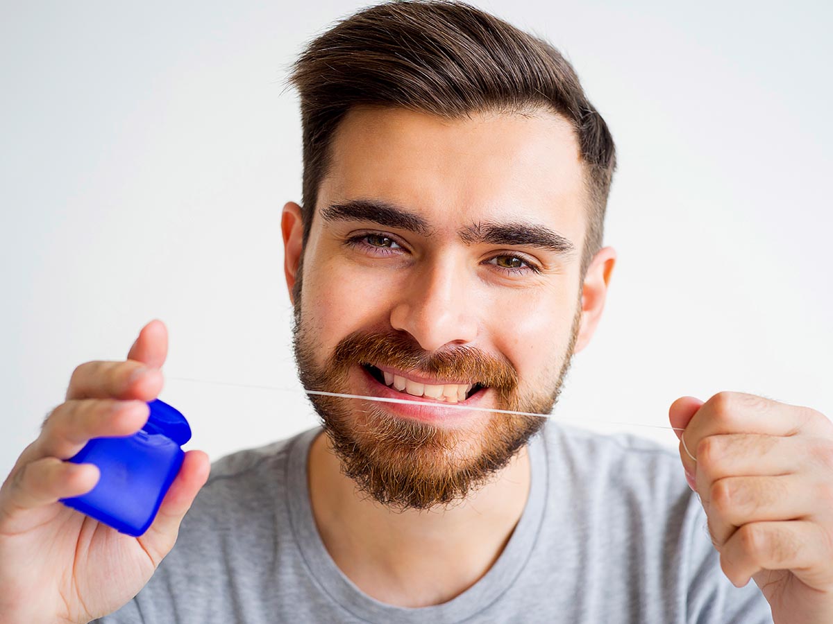 Smiling man holding up dental floss