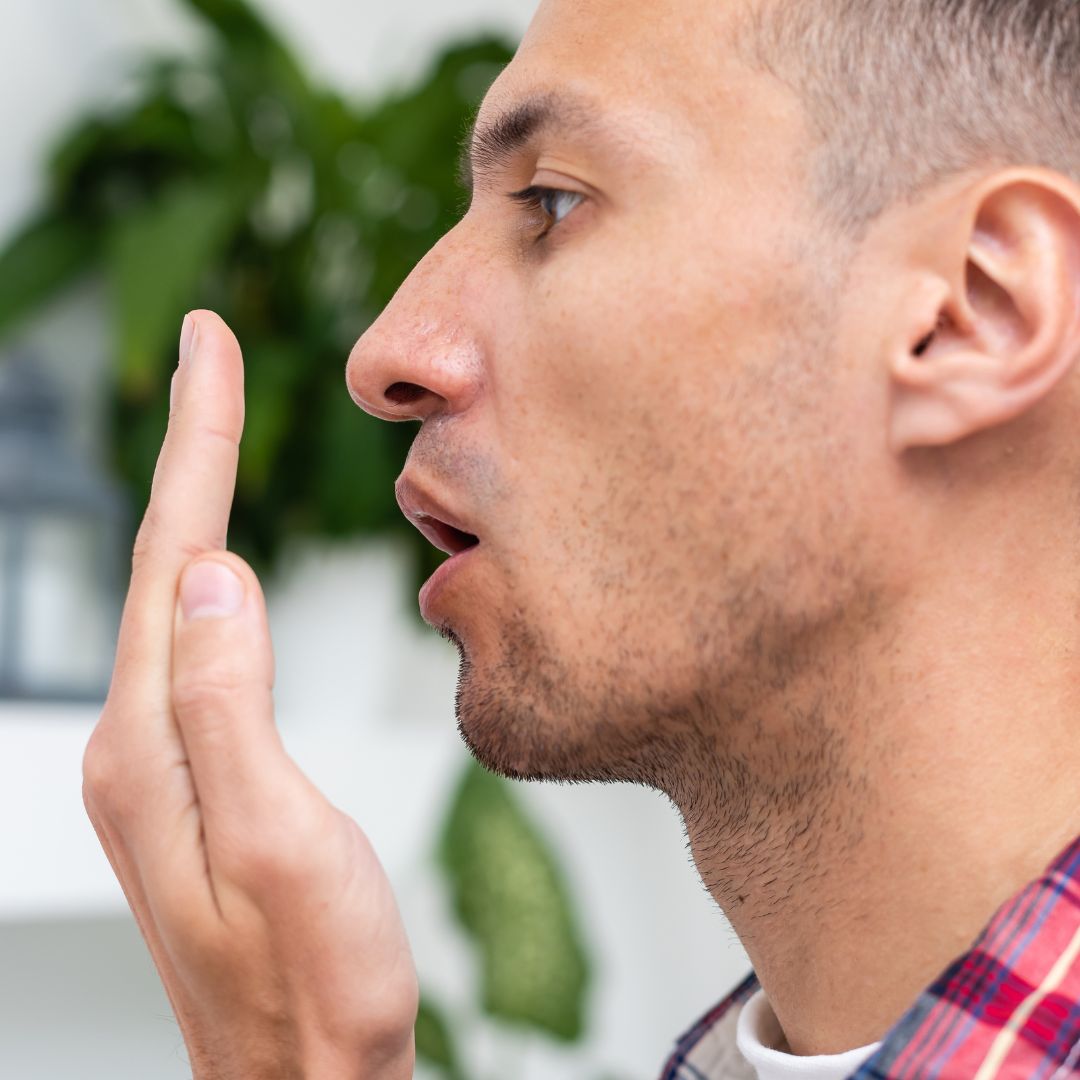 man checking his breath against his hand