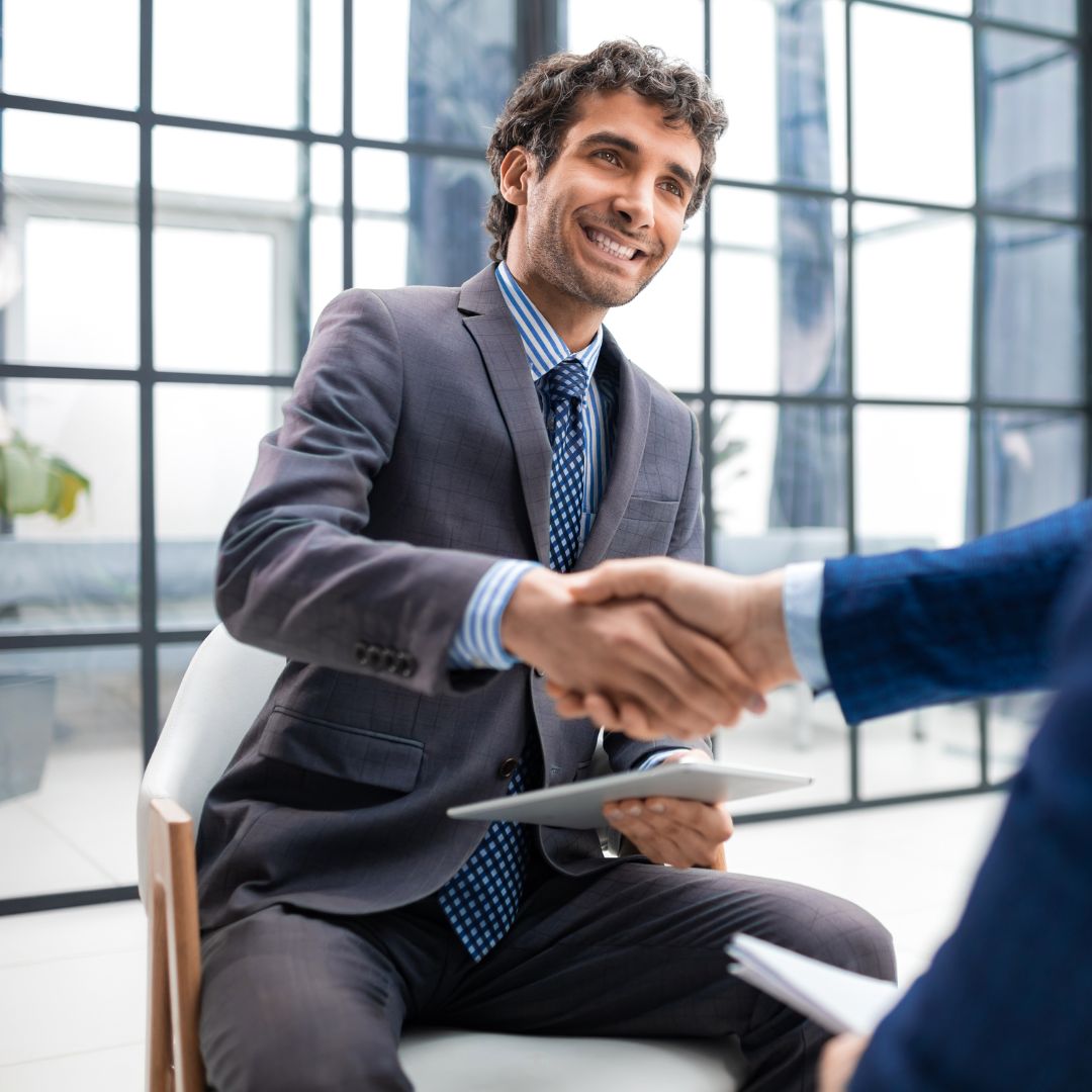 a man in a suit smiling and shaking hands