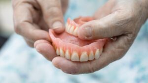 Hands holding a pair of full dentures