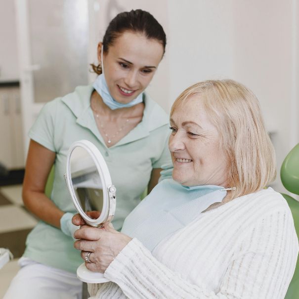 Elderly woman viewing dentures with dentist