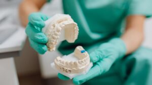 holding model of mouth and teeth